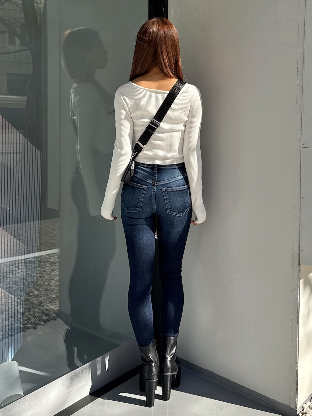 ホワイト系のニット/セーター、ブルー系のデニムパンツ、ブラック系のブーツを着用したレディースの冬コーディネートの3枚目の写真