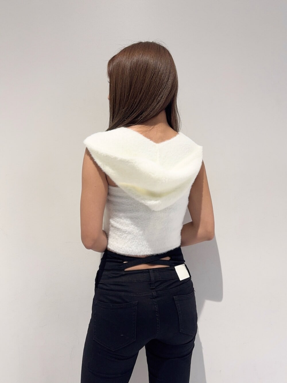 ブラック系のデニムパンツ、ブラック系のブーツ、ホワイト系のニット/セーターを着用したレディースの秋コーディネートの5枚目の写真