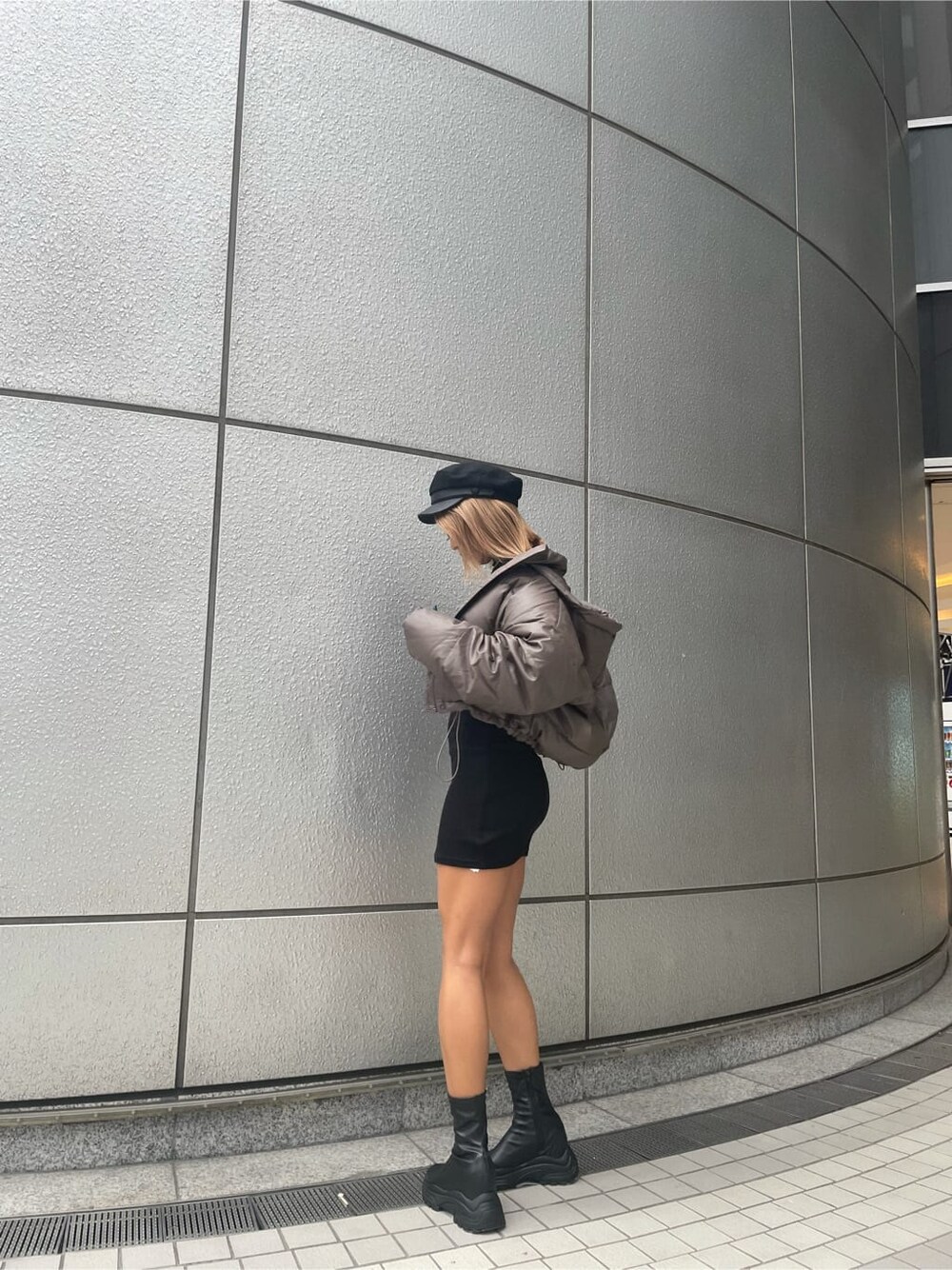 ベージュ系のダウンジャケット/コート、ブラック系のブーツ、ブラック系のワンピースを着用したレディースの秋コーディネートの3枚目の写真