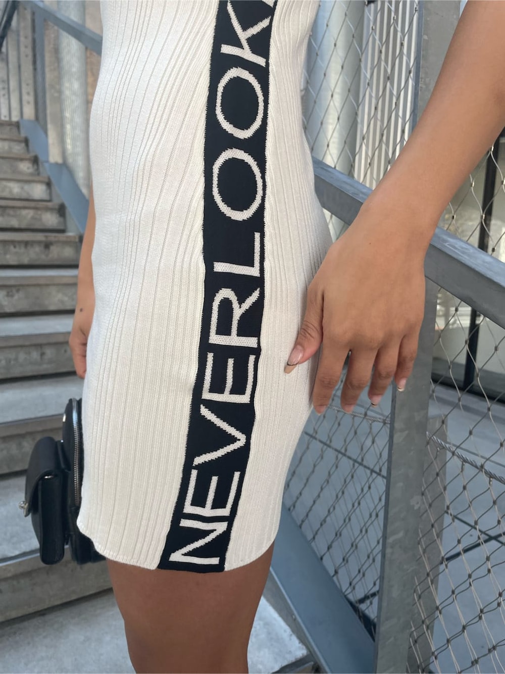 ブラック系のパンプス、ホワイト系のワンピース、ブラック系のバックパック/リュックを着用したレディースの春コーディネートの4枚目の写真