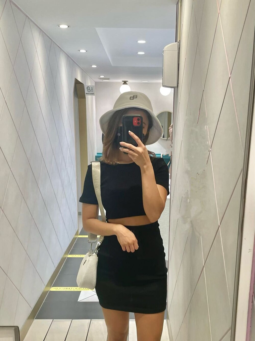 ブラック系のワンピース、ブラック系のサンダル、ホワイト系のハンドバッグを着用したレディースの春コーディネートの7枚目の写真