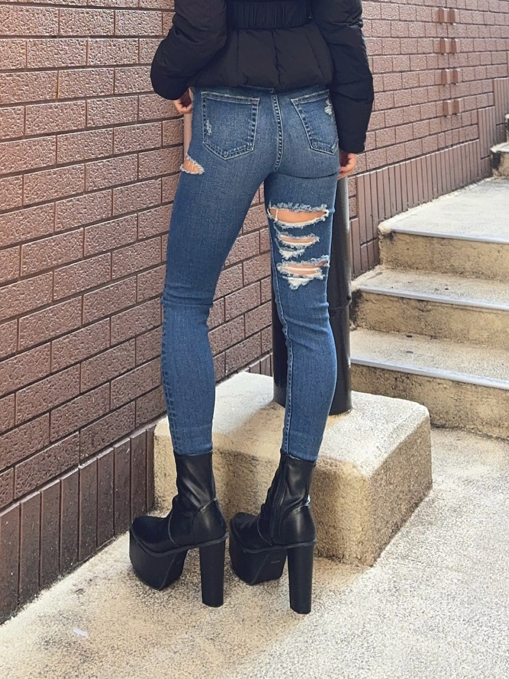 ブラック系のダウンジャケット/コート、ブラック系のニット/セーター、ブルー系のデニムパンツを着用したレディースの秋コーディネートの8枚目の写真