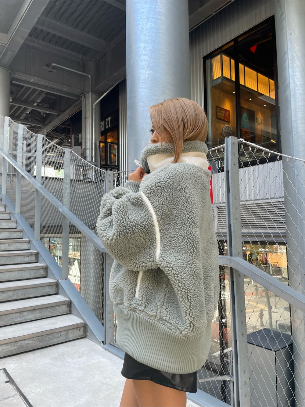 ブラック系のスカート、ホワイト系のニット/セーター、ブラック系のブーツを着用したレディースの秋コーディネートの5枚目の写真