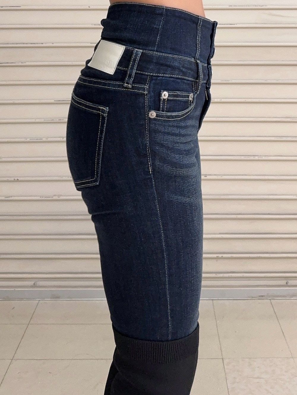 ブラック系のニット/セーター、ブルー系のデニムパンツ、ブラック系のブーツを着用したレディースの秋コーディネートの6枚目の写真