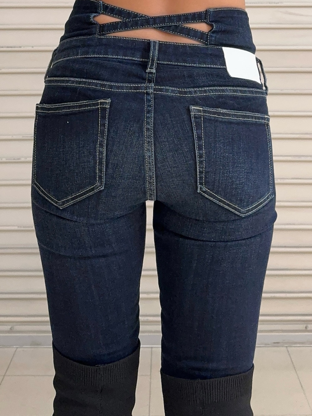 ブラック系のニット/セーター、ブルー系のデニムパンツ、ブラック系のブーツを着用したレディースの秋コーディネートの7枚目の写真