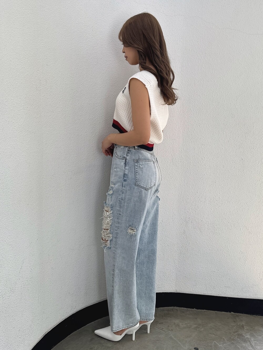 ホワイト系のニット/セーター、ブルー系のデニムパンツ、ホワイト系のパンプスを着用したレディースの春コーディネートの3枚目の写真