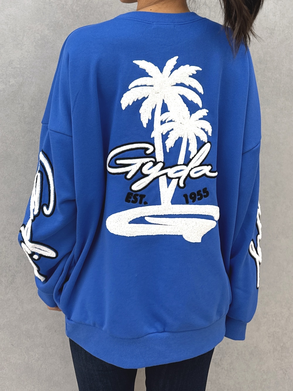 ブルー系のスウェット、ブルー系のデニムパンツ、ブラック系のブーツを着用したレディースの秋コーディネートの5枚目の写真