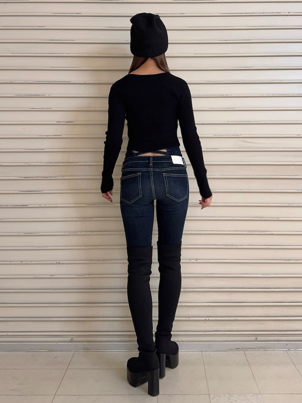 ブラック系のニット/セーター、ブルー系のデニムパンツ、ブラック系のブーツを着用したレディースの秋コーディネートの3枚目の写真