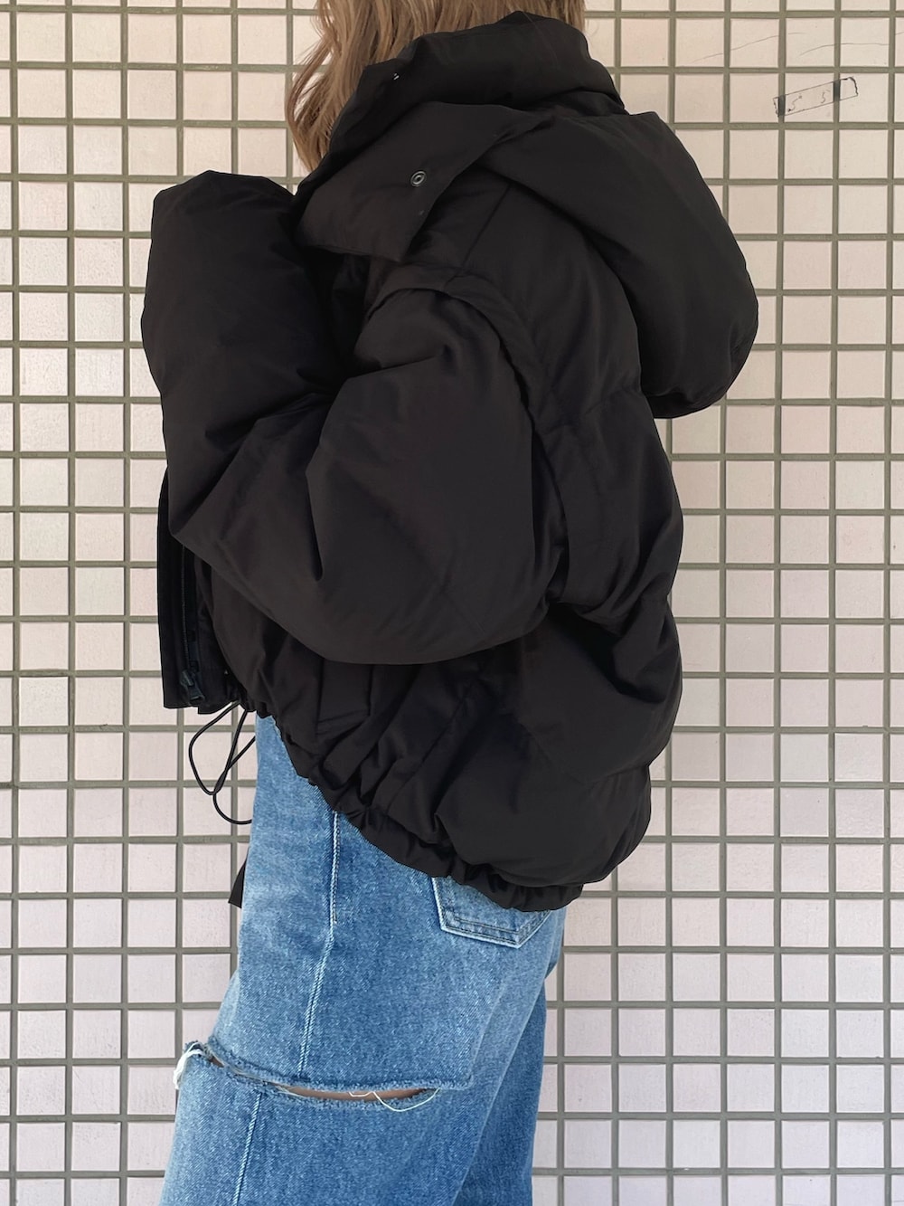 ホワイト系のスニーカー、ブルー系のデニムパンツ、ブラック系のニット/セーターを着用したレディースの冬コーディネートの7枚目の写真