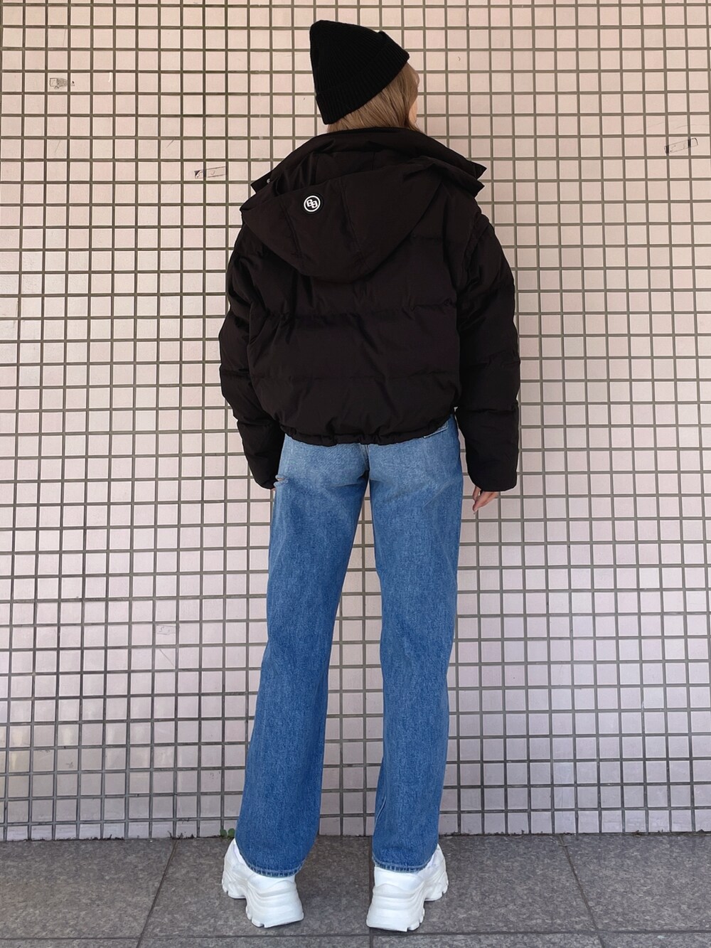 ホワイト系のスニーカー、ブルー系のデニムパンツ、ブラック系のニット/セーターを着用したレディースの冬コーディネートの4枚目の写真