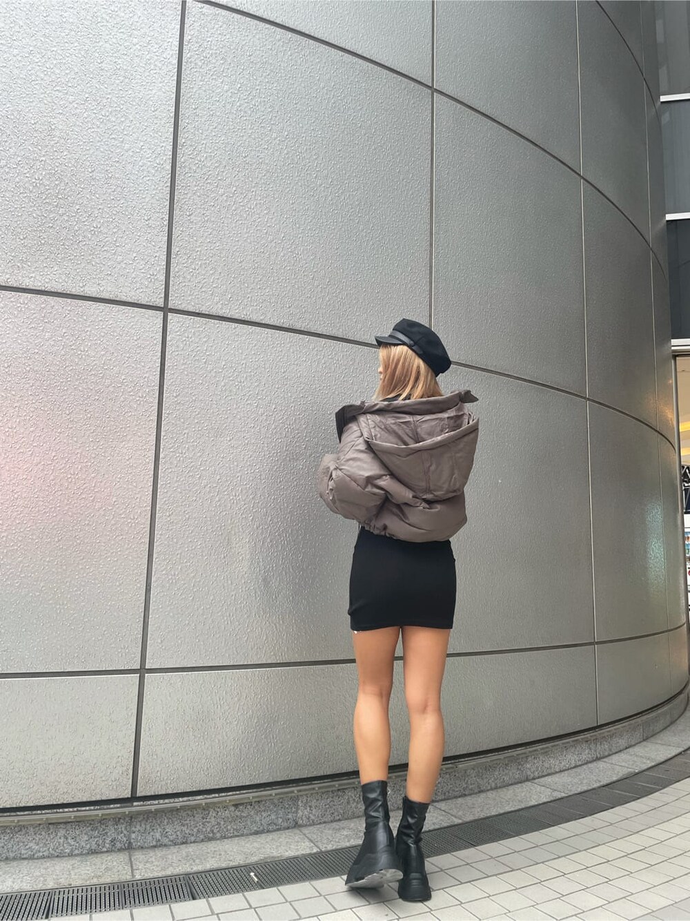 ベージュ系のダウンジャケット/コート、ブラック系のブーツ、ブラック系のワンピースを着用したレディースの秋コーディネートの2枚目の写真