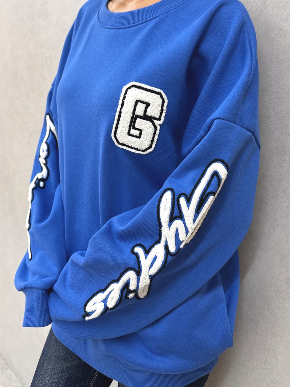 ブルー系のスウェット、ブルー系のデニムパンツ、ブラック系のブーツを着用したレディースの秋コーディネートの7枚目の写真