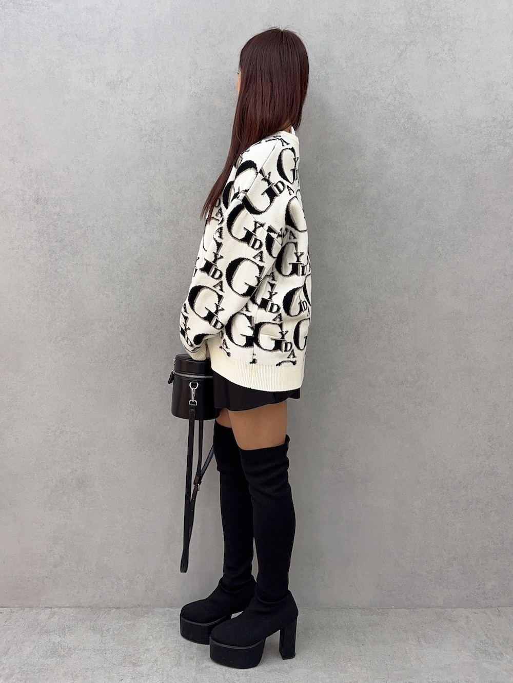 ホワイト系のニット/セーター、ブラック系のスカート、ブラック系のハンドバッグを着用したレディースの冬コーディネートの2枚目の写真