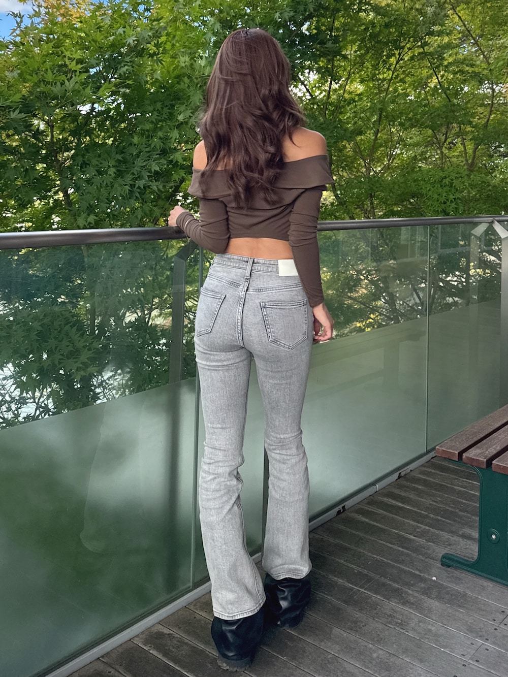 グリーン系のTシャツ/カットソー、グレー系のデニムパンツ、ブラック系のブーツを着用したレディースの秋コーディネートの3枚目の写真