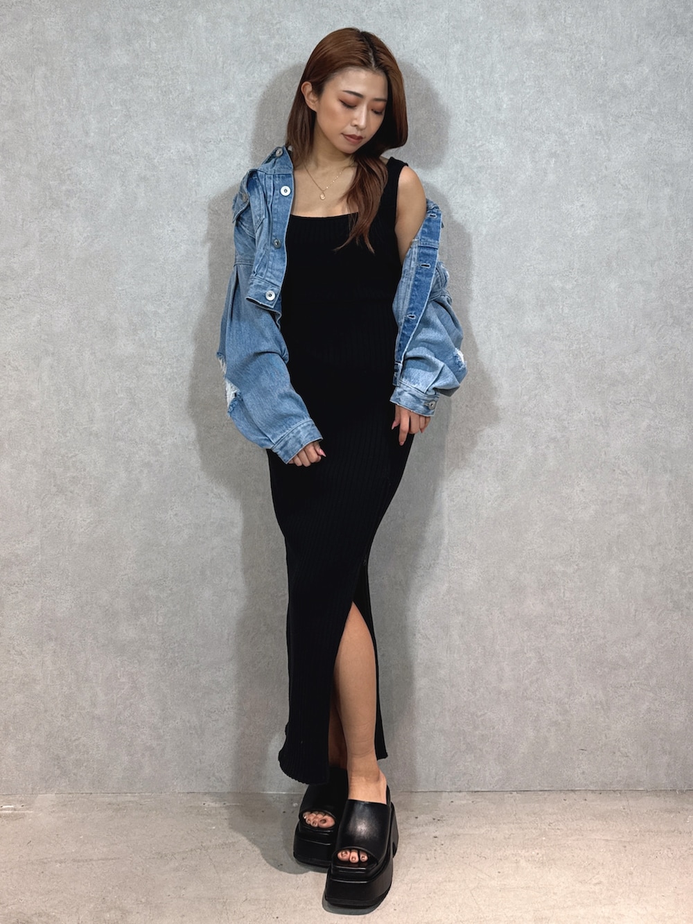 ブラック系のワンピース、ブルー系のデニムジャケット、ブラック系のサンダルを着用したレディースの春コーディネートの2枚目の写真