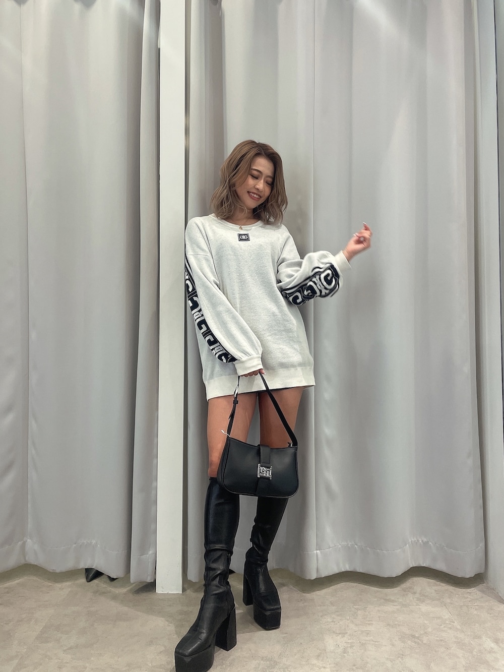 ブラック系のブーツ、ブラック系のハンドバッグ、ホワイト系のニット/セーターを着用したレディースの冬コーディネートの3枚目の写真