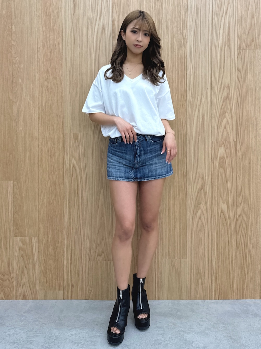 ホワイト系のTシャツ/カットソー、ブルー系のデニムスカート、ブラック系のブーツを着用したレディースの春コーディネートの4枚目の写真