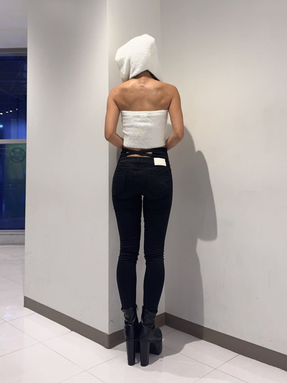 ブラック系のデニムパンツ、ブラック系のブーツ、ホワイト系のニット/セーターを着用したレディースの秋コーディネートの3枚目の写真