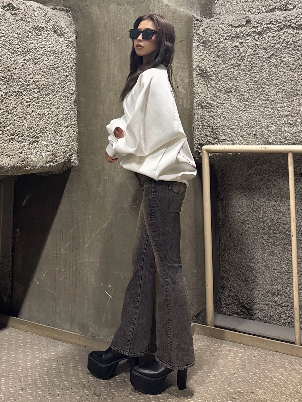 ホワイト系のスウェット、ブルー系のデニムパンツ、ブラック系のブーツを着用したレディースの冬コーディネートの2枚目の写真