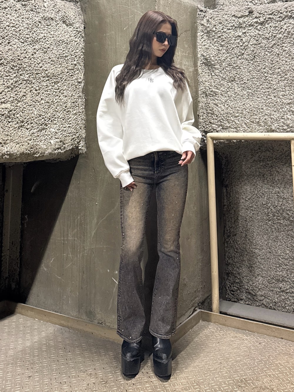 ホワイト系のスウェット、ブルー系のデニムパンツ、ブラック系のブーツを着用したレディースの冬コーディネートの3枚目の写真