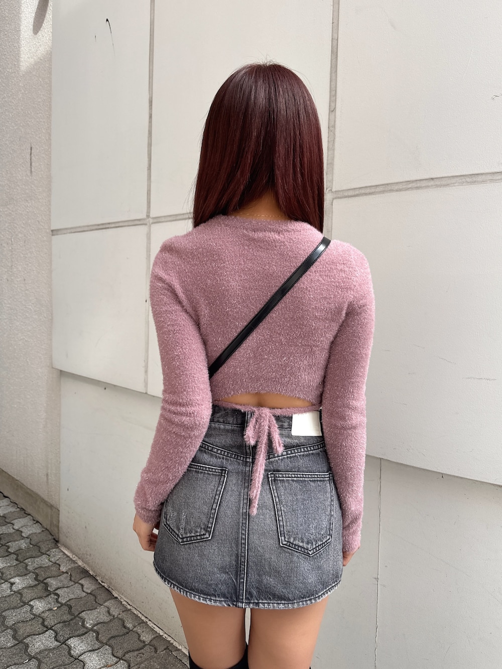 ピンク系のニット/セーター、ブラック系のデニムスカート、ブラック系のブーツを着用したレディースの冬コーディネートの5枚目の写真