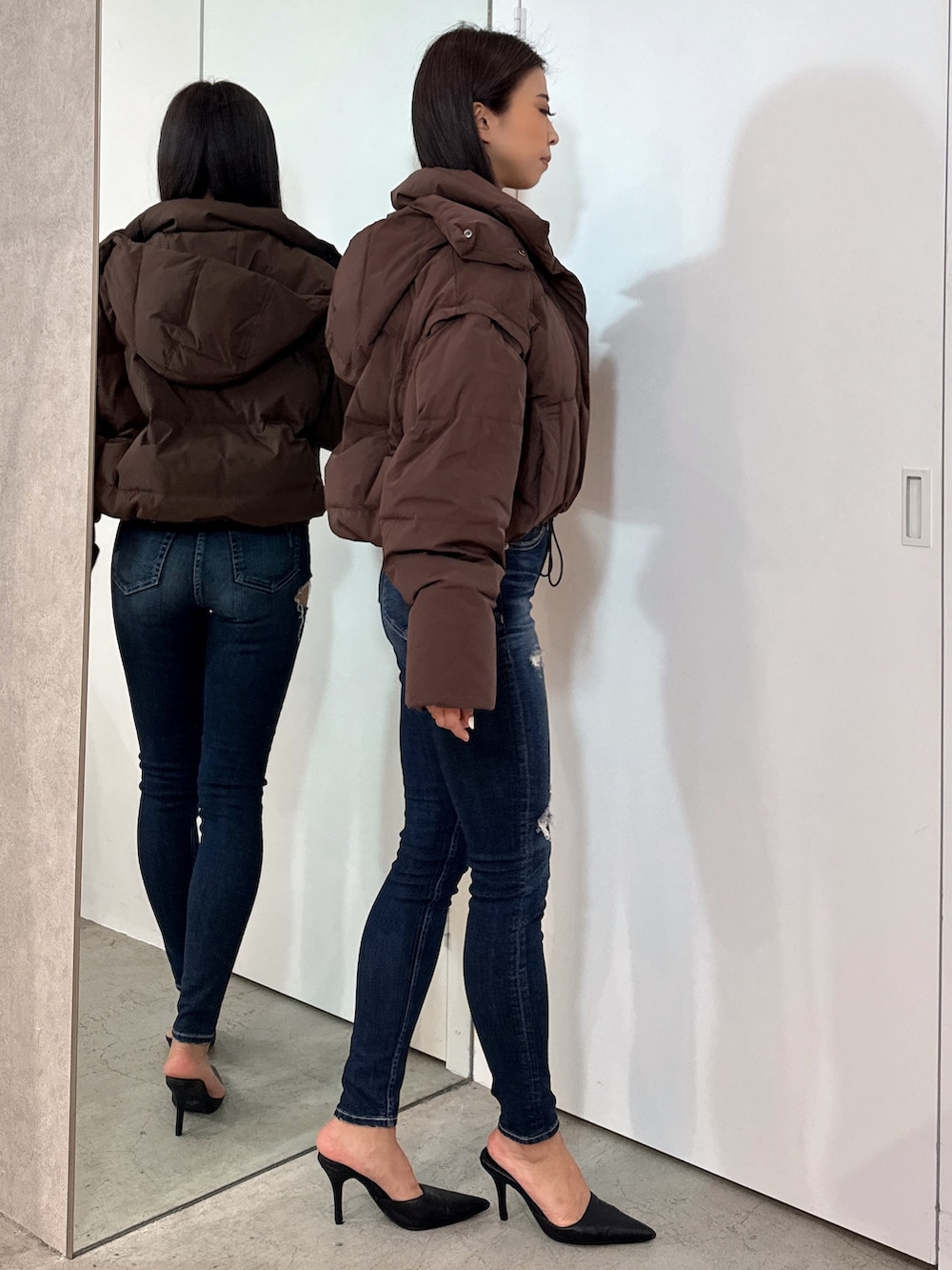 ホワイト系のTシャツ/カットソー、ブラウン系のダウンジャケット/コート、ブルー系のデニムパンツを着用したレディースの秋コーディネートの3枚目の写真