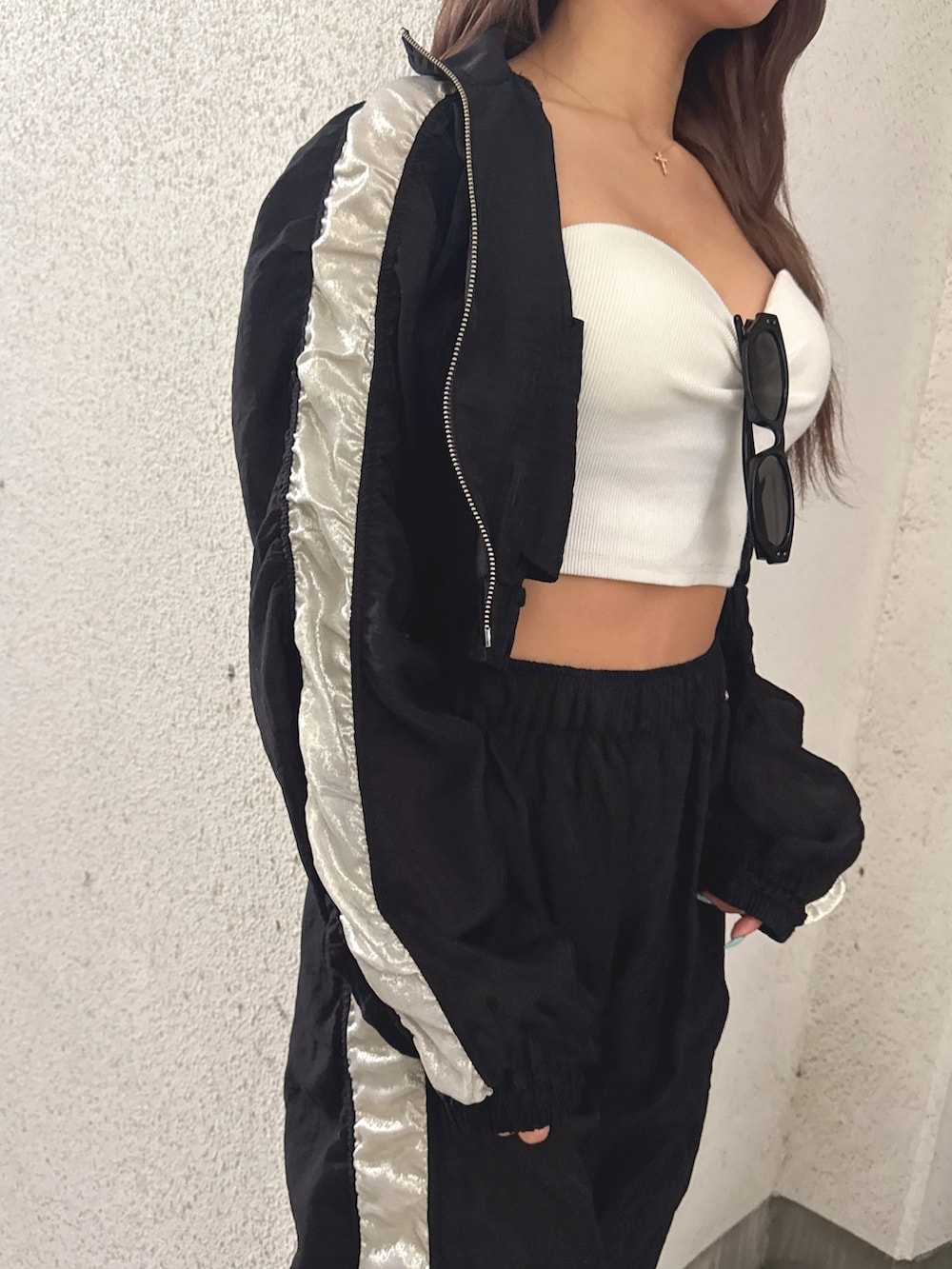 ホワイト系のチューブトップ、ブラック系のブルゾン、ブラック系のその他パンツを着用したレディースの春コーディネートの5枚目の写真