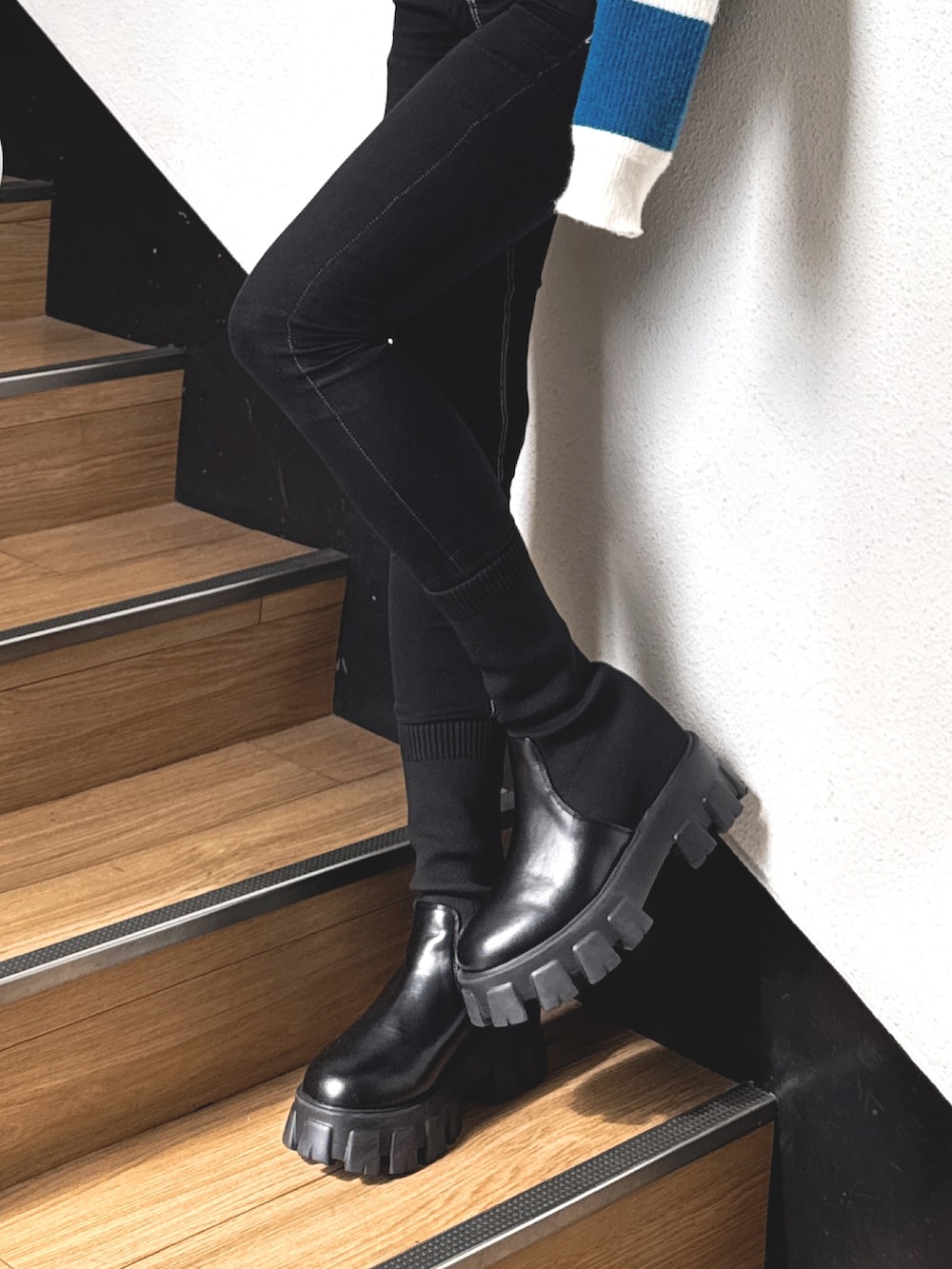 ブルー系のニット/セーター、ブラック系のデニムパンツ、ブラック系のブーツを着用したレディースの秋コーディネートの7枚目の写真