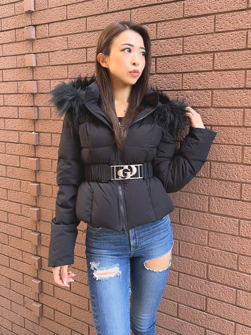 ブラック系のダウンジャケット/コート、ブラック系のニット/セーター、ブルー系のデニムパンツを着用したレディースの秋コーディネートの5枚目の写真