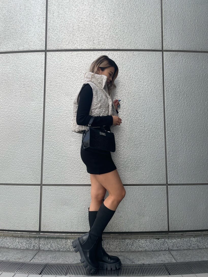 ブラック系のハンドバッグ、ブラック系のワンピース、ブラック系のブーツを着用したレディースの秋コーディネートの4枚目の写真