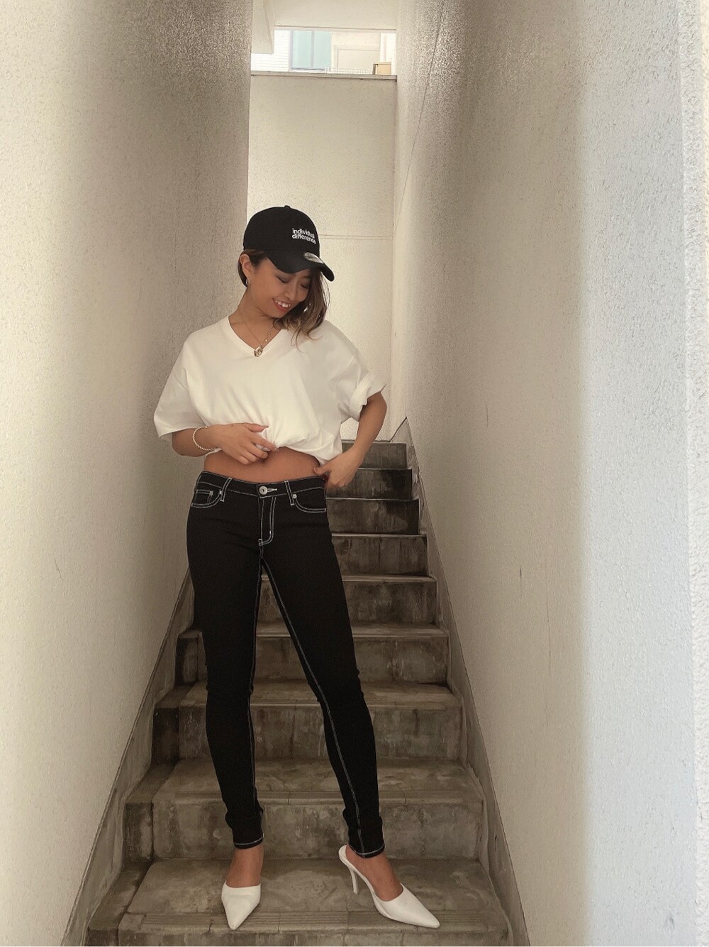 ホワイト系のTシャツ/カットソー、ホワイト系のパンプス、ブラック系のデニムパンツを着用したレディースの春コーディネートの2枚目の写真