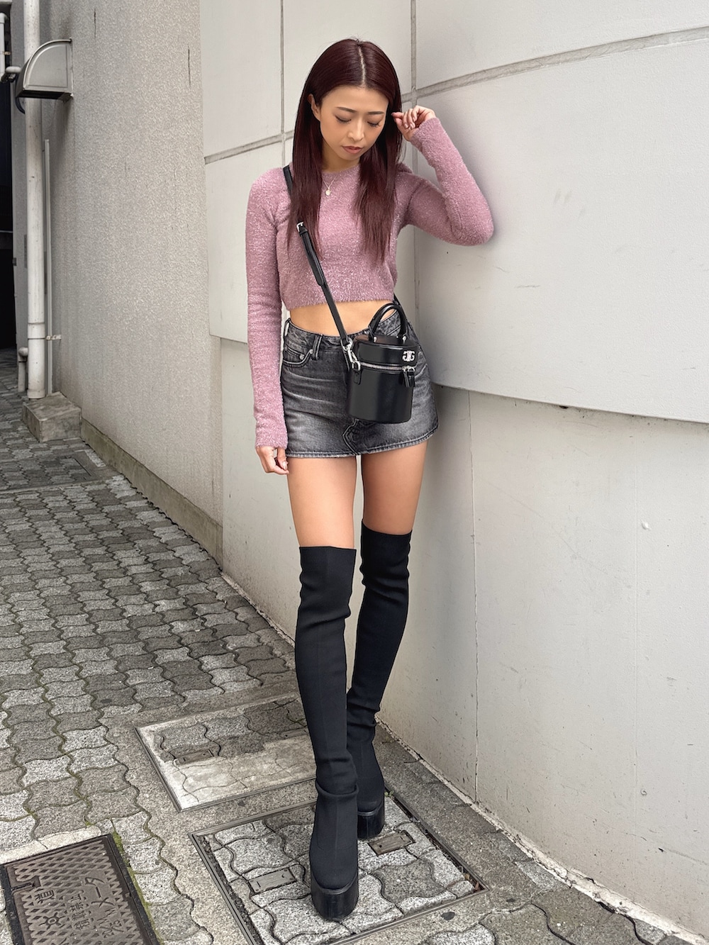 ピンク系のニット/セーター、ブラック系のデニムスカート、ブラック系のブーツを着用したレディースの冬コーディネートの2枚目の写真