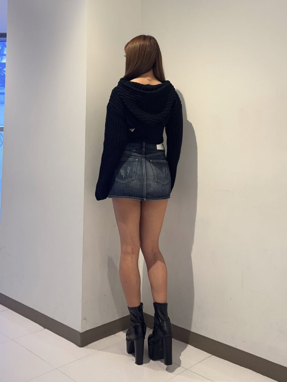 ブラック系のブーツ、ブルー系のデニムスカート、ブラック系のニット/セーターを着用したレディースの秋コーディネートの3枚目の写真