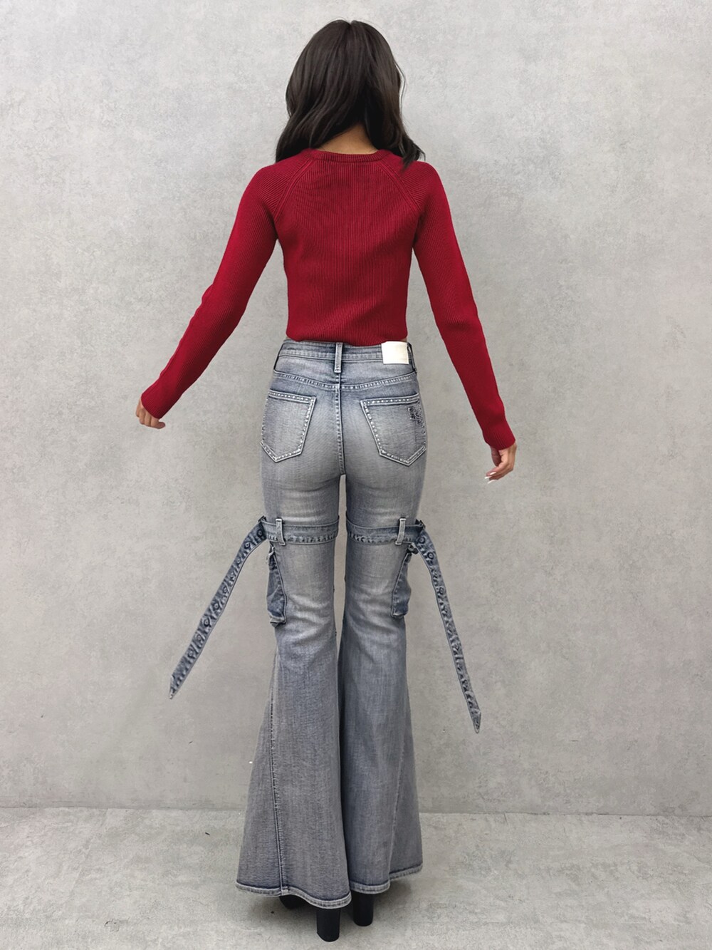 レッド系のニット/セーター、ブルー系のデニムパンツ、ブラック系のブーツを着用したレディースの夏コーディネートの3枚目の写真