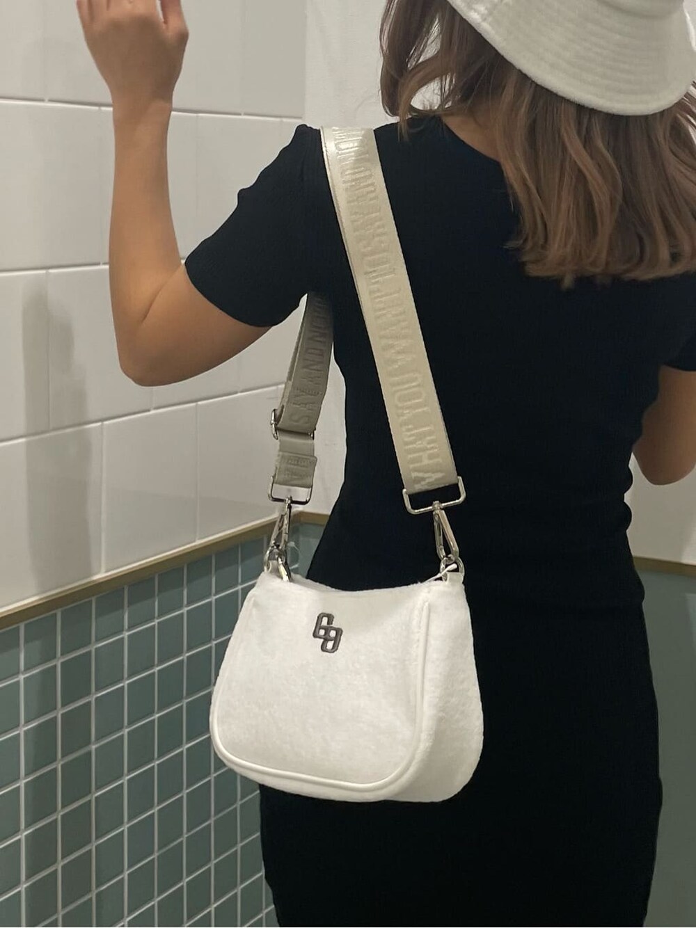 ブラック系のワンピース、ブラック系のサンダル、ホワイト系のハンドバッグを着用したレディースの春コーディネートの5枚目の写真