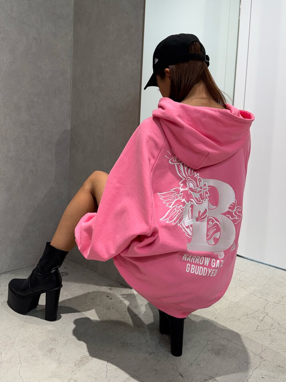 ピンク系のパーカー、ブラック系のショルダーバッグ、ブラック系のブーツを着用したレディースの冬コーディネートの3枚目の写真