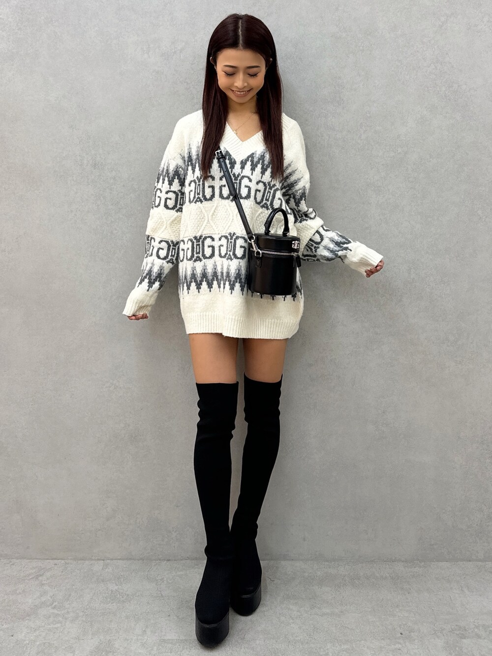 ホワイト系のニット/セーター、ブラック系のハンドバッグ、ブラック系のブーツを着用したレディースの冬コーディネートの2枚目の写真