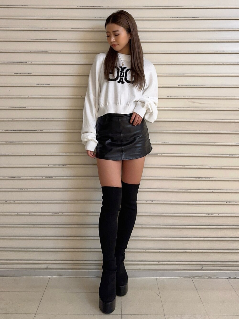 ホワイト系のニット/セーター、ブラック系のスカート、ブラック系のブーツを着用したレディースの秋コーディネートの2枚目の写真