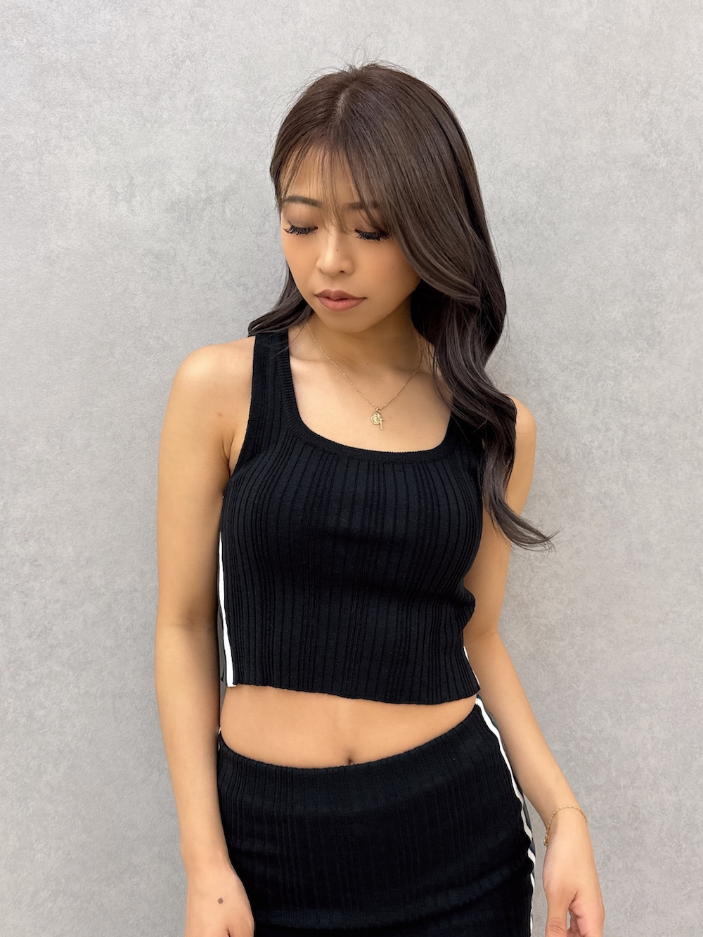 ブラック系のニット/セーター、ブラック系のスカート、ブラック系のサンダルを着用したレディースの夏コーディネートの4枚目の写真