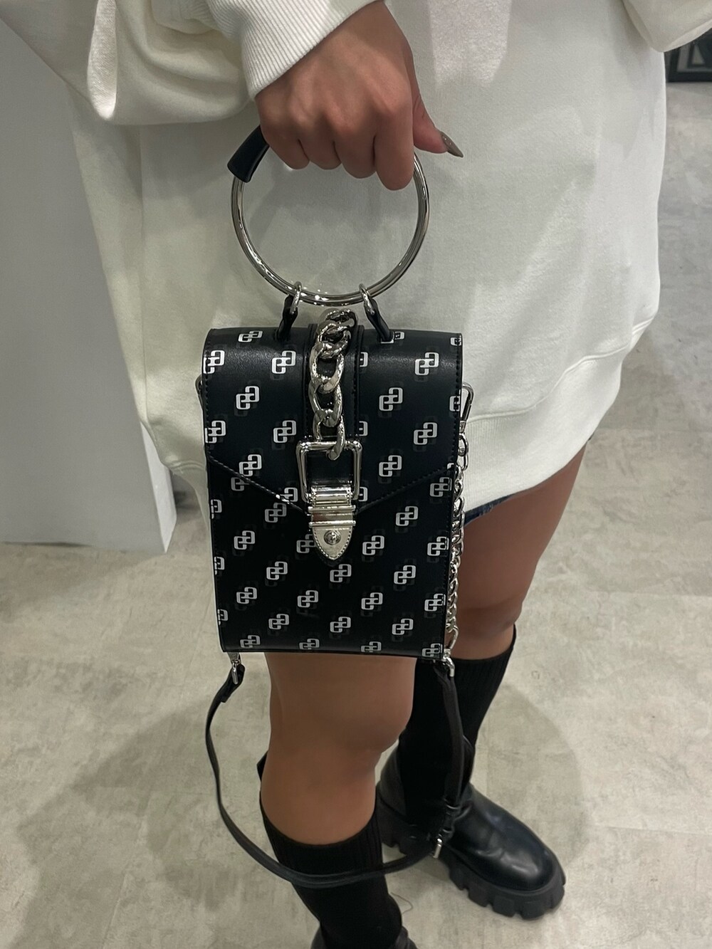 ホワイト系のスウェット、ブルー系のデニムスカート、ブラック系のショルダーバッグを着用したレディースの冬コーディネートの7枚目の写真