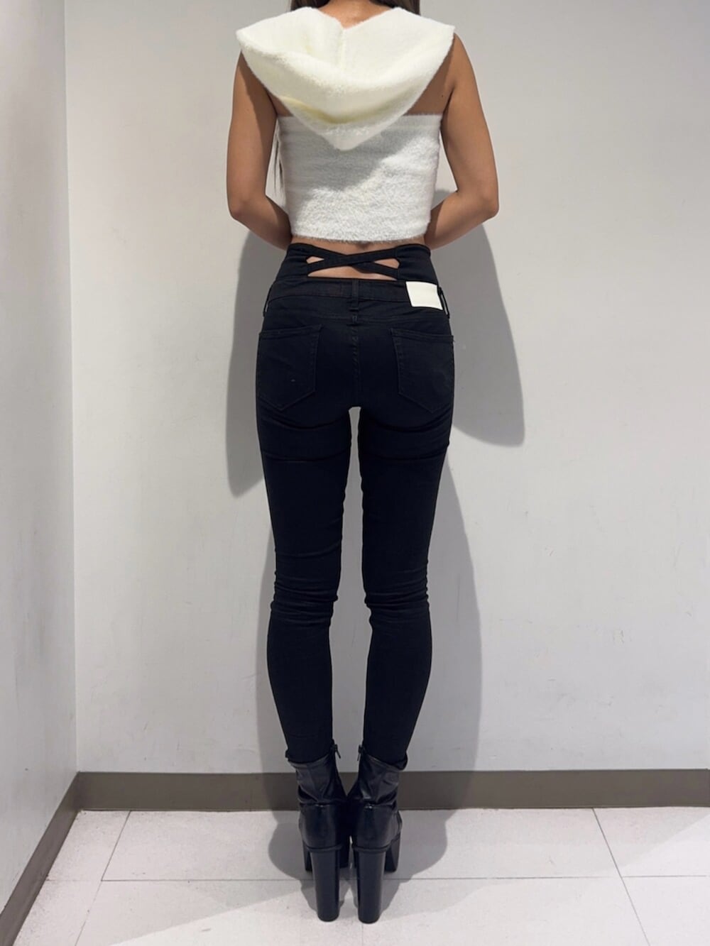 ブラック系のデニムパンツ、ブラック系のブーツ、ホワイト系のニット/セーターを着用したレディースの秋コーディネートの7枚目の写真