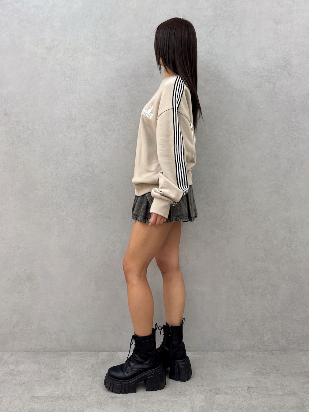 ベージュ系のスウェット、ブルー系のデニムスカート、ブラック系のブーツを着用したレディースの春コーディネートの3枚目の写真