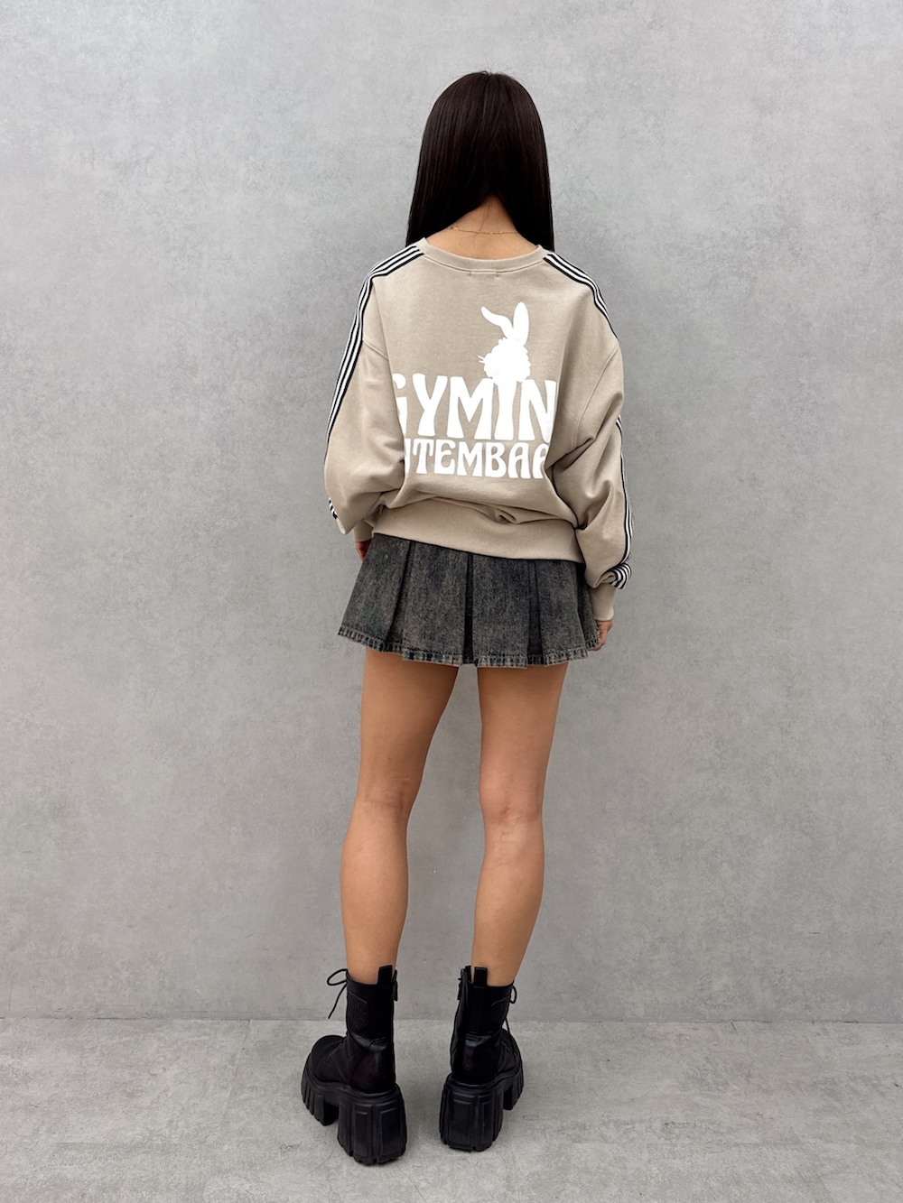 ベージュ系のスウェット、ブルー系のデニムスカート、ブラック系のブーツを着用したレディースの春コーディネートの4枚目の写真