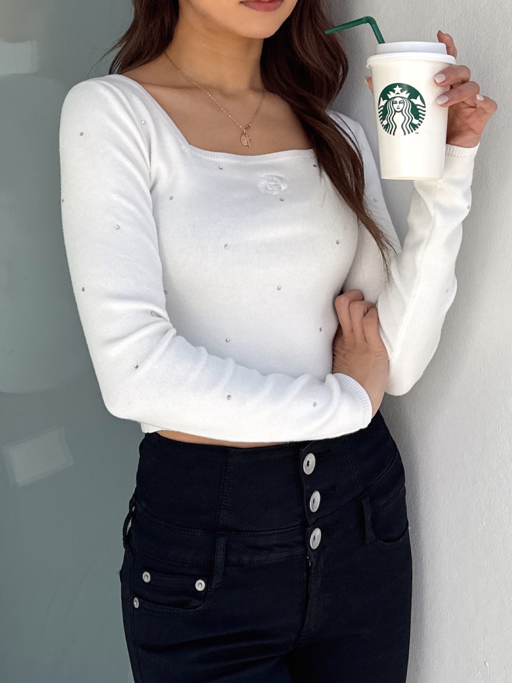 ホワイト系のニット/セーター、ブラック系のデニムパンツ、ホワイト系のパンプスを着用したレディースの春コーディネートの6枚目の写真