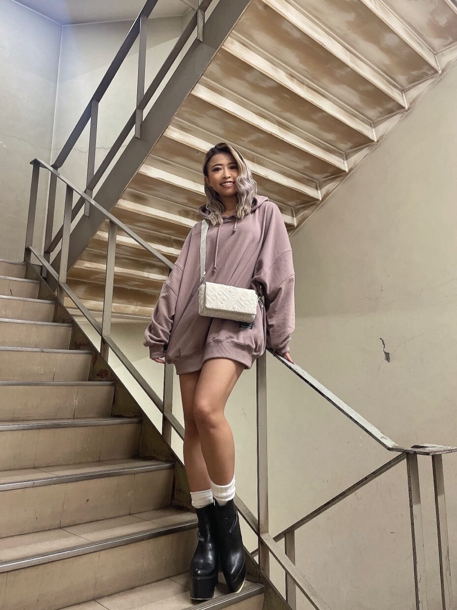 ブラック系のブーツ、ホワイト系のショルダーバッグ、ピンク系のパーカーを着用したレディースの秋コーディネートの2枚目の写真