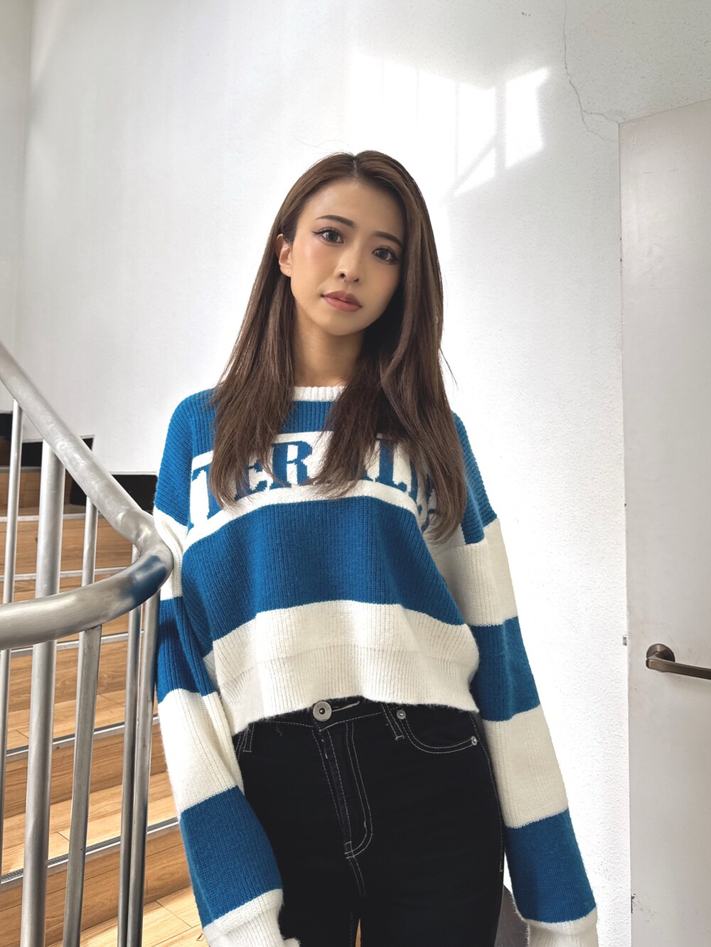 ブルー系のニット/セーター、ブラック系のデニムパンツ、ブラック系のブーツを着用したレディースの秋コーディネートの4枚目の写真