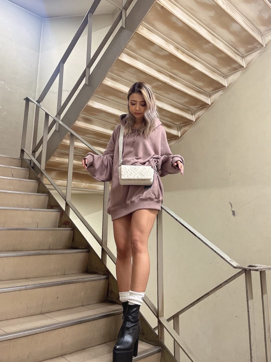 ブラック系のブーツ、ホワイト系のショルダーバッグ、ピンク系のパーカーを着用したレディースの秋コーディネートの3枚目の写真