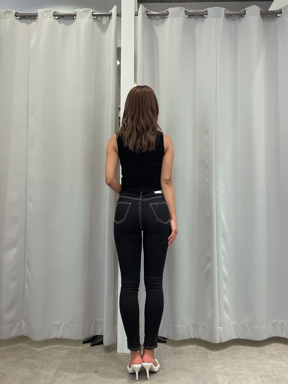 ブラック系のニット/セーター、ブラック系のデニムパンツ、ホワイト系のパンプスを着用したレディースの夏コーディネートの3枚目の写真