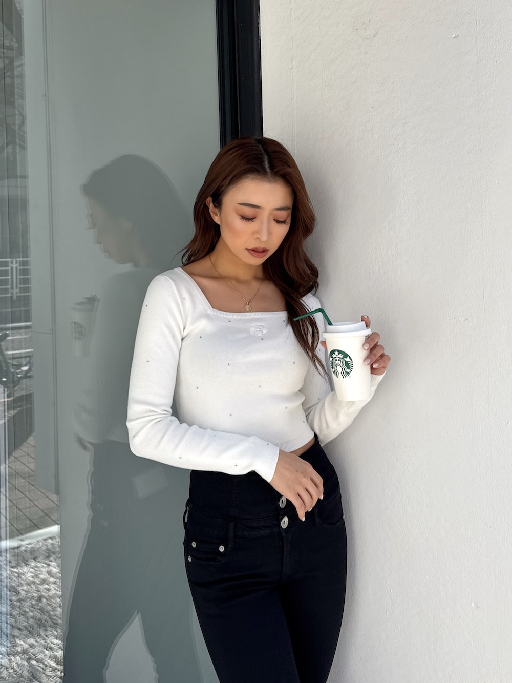 ホワイト系のニット/セーター、ブラック系のデニムパンツ、ホワイト系のパンプスを着用したレディースの春コーディネートの5枚目の写真