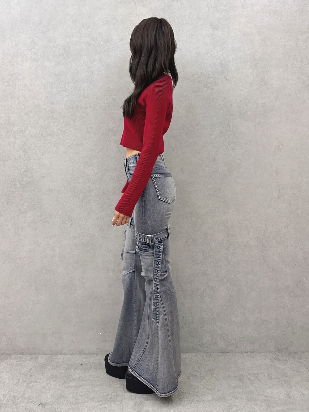 レッド系のニット/セーター、ブルー系のデニムパンツ、ブラック系のブーツを着用したレディースの夏コーディネートの2枚目の写真